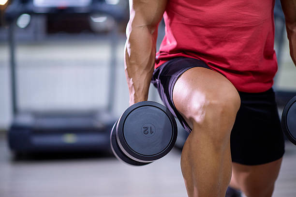 Close-up of a muscled man doing weight exercises for strength in a modern gym.